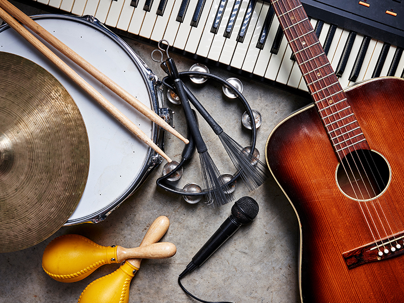 a group of musical instruments including a guitar, drum, keyboard, tambourine.