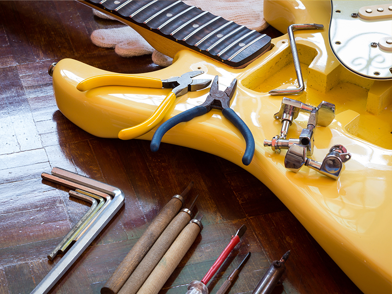 Guitar on table being repaired with tools scattered around